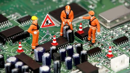 Miniature Repair Crew at Work on Circuit Board wallpaper