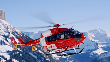 Red Helicopter Soaring Over Majestic Mountains wallpaper