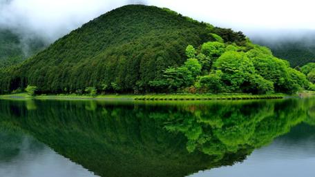 Misty Lake Reflection Amidst Verdant Hills wallpaper