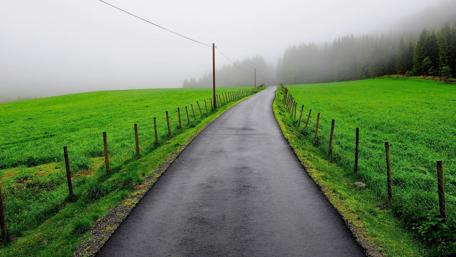 Misty Road through Lush Green Landscape wallpaper