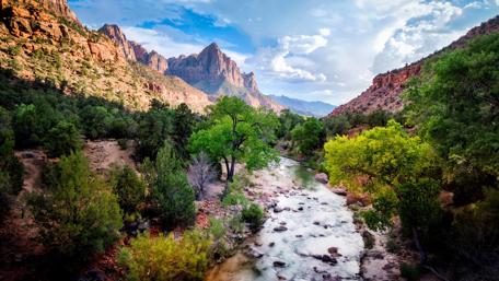 Serene Stream Flowing Through Majestic Hills wallpaper