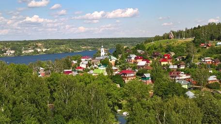 Serene Village by the River Amidst Lush Greenery wallpaper