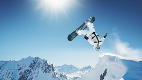 Snowboarder Soaring Over Majestic Mountains wallpaper