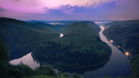 Serene River Winding Through Lush Forest Hillside wallpaper