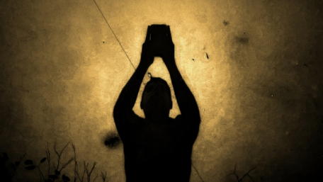 Silhouette of a Tech Enthusiast Holding a Device wallpaper