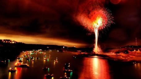 Vibrant Night Over Waterway with Fireworks Display wallpaper