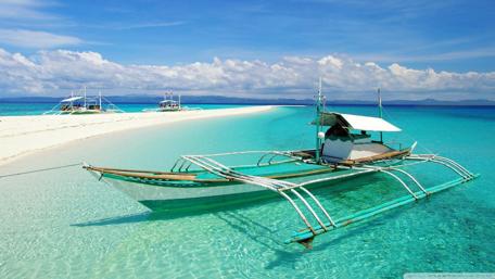 Serene Beach with Traditional Boat Amidst Turquoise Waters wallpaper