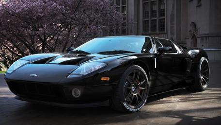 Sleek Black Supercar Under Cherry Blossoms wallpaper