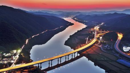 Serene Cityscape at Dusk Overlooking a River and Mountains wallpaper