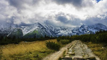 Majestic Mountain Pathway Under Cloudy Skies wallpaper
