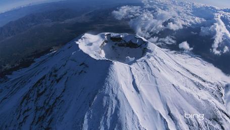 Majestic Snow-Capped Volcano Under Cloudy Skies wallpaper