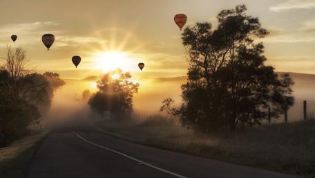 Breathtaking Sunrise Over Misty Landscape with Hot Air Balloons wallpaper