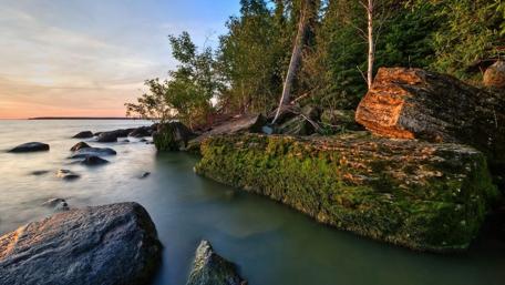 Serene Lakeside Forest Scene with Mossy Rocks wallpaper