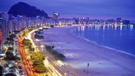 Cityscape at Dusk with Beach Views and Vibrant Lights wallpaper