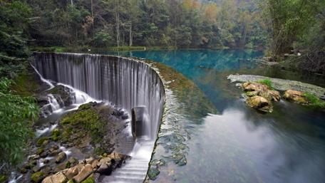 Tranquil Waterfall Amidst Lush Greenery wallpaper
