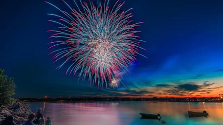 Vibrant Fireworks Over the Water Night Sky wallpaper