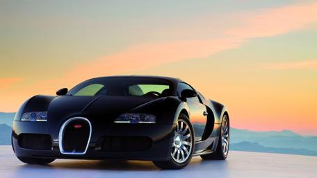 Sleek Black Car Against a Vibrant Sunset Landscape wallpaper