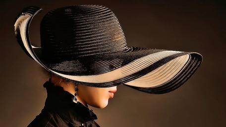Elegant Woman in a Dramatic Hat Displaying Unique Style and Graceful Beauty wallpaper