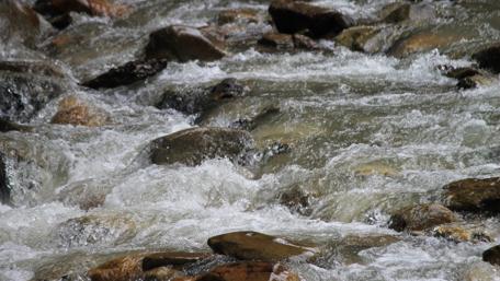 Serene River Flowing Through Rocky Landscape wallpaper
