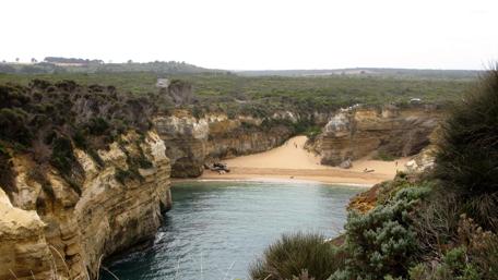 Serene Coastal Landscape with Sandy Beach and Lush Cliffs wallpaper