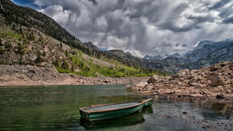 Serene Lake with a Boat Under Dramatic Clouds wallpaper