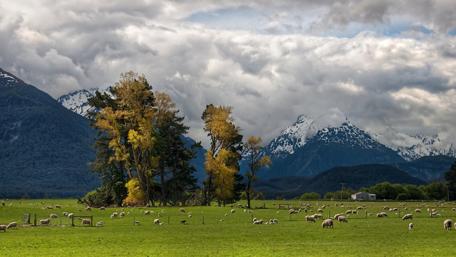 Majestic Landscape of Mountains and Sheep Pasture wallpaper
