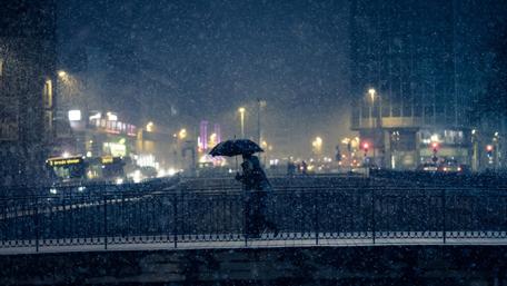 Winter Stroll Under Snowy City Lights wallpaper