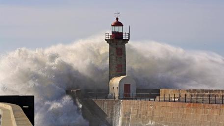 Majestic Lighthouse Amidst Powerful Waves wallpaper