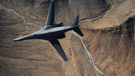 Soaring Fighter Jet Over Arid Landscape wallpaper