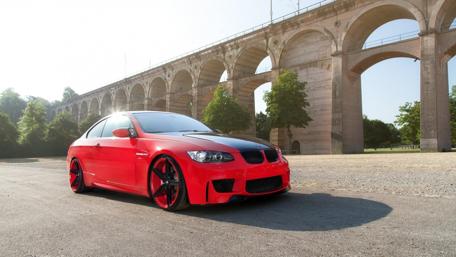Sleek Red Sports Car Under Arched Bridge wallpaper