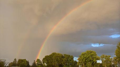 Rainbow Glowing Through Cloudy Skies wallpaper
