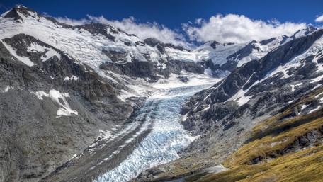 Majestic Glacier Flowing Through Rugged Mountains wallpaper