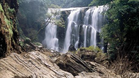 Majestic Waterfall Glimpse in Lush Greenery wallpaper
