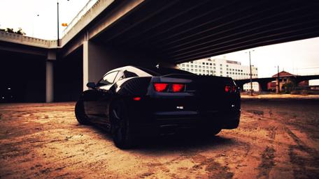 Sleek Black Car Under Urban Overpass wallpaper
