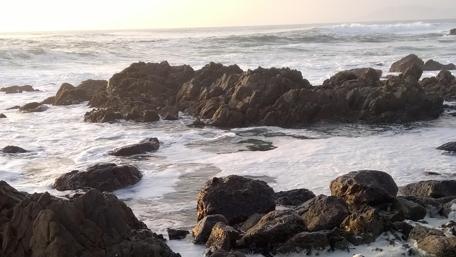 Serene Waves Against Rocky Shoreline wallpaper