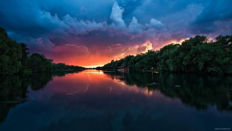 Majestic Lightning Over a Serene River Scene wallpaper