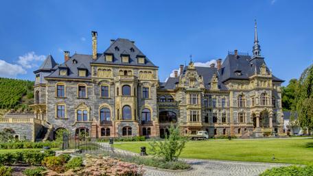 Majestic Castle Surrounded by Lush Gardens and Blue Skies wallpaper