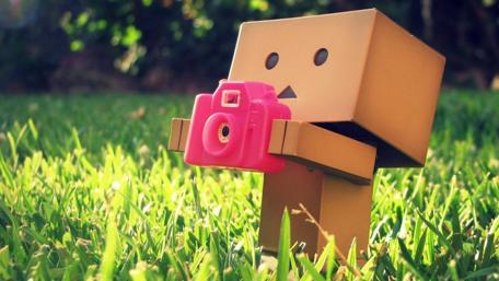 Whimsical Cardboard Man Capturing Nature Moments wallpaper