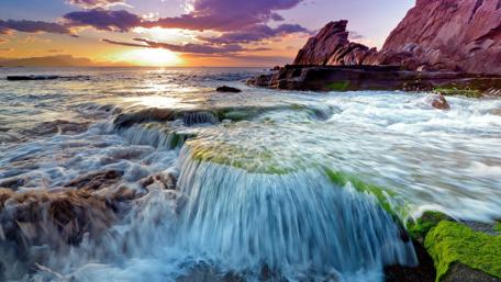 Serene Sunset Over a Majestic Waterfall wallpaper