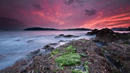 Vibrant Sunset Over Rocky Shoreline wallpaper