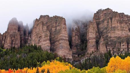 Misty Cliffs Surrounded by Forests and Rocky Peaks wallpaper