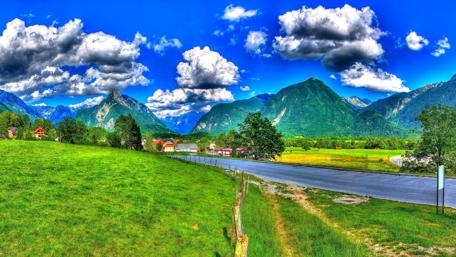 Mountain Village Serenity in Vibrant Green and Blue Sky wallpaper