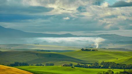 Serene Cloudy Landscape Over Lush Fields wallpaper