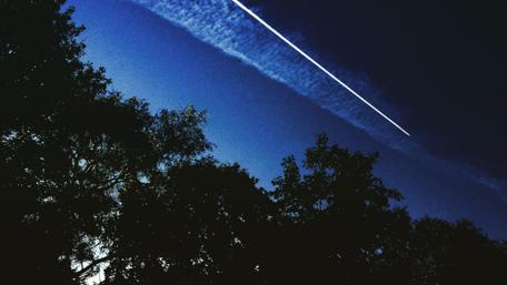 Serene Night Sky with Contrails and Silhouetted Trees wallpaper