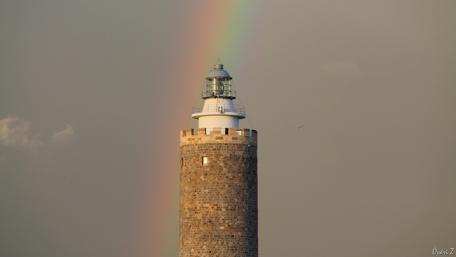 Lighthouse Under a Vibrant Rainbow Sky wallpaper