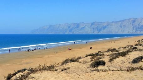Serene Beach with Majestic Cliffs and Clear Blue Sky wallpaper