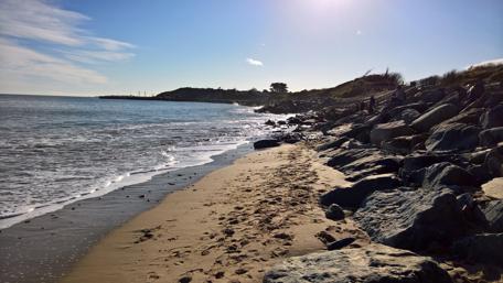 Serene Beach Escape with Rocky Shoreline and Gentle Waves wallpaper