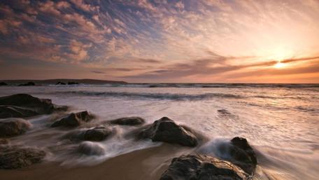 Serene Sunset Over a Rocky Shoreline wallpaper