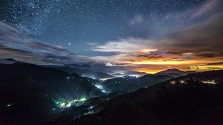 Starry Night over Illuminated Mountains wallpaper