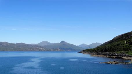Serene Shoreline with Majestic Mountains and Clear Sky wallpaper